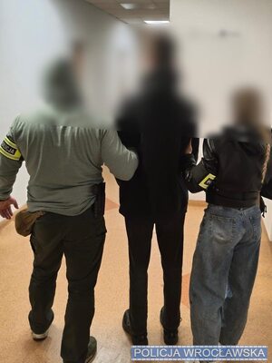 policjant i policjantka prowadzą zatrzymanego.