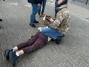 zatrzymany leży na ziemi. pilnuje go policjant.