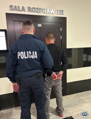 Policjant prowadzi zatrzymanego.