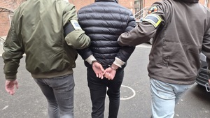 policjanci prowadzą zatrzymanego.