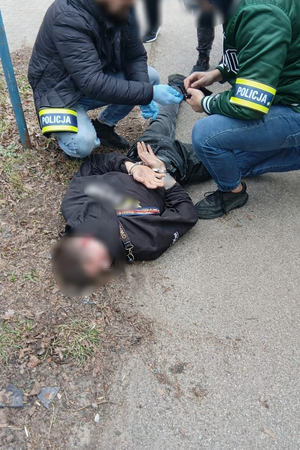 policjanci prowadzą zatrzymanego.
