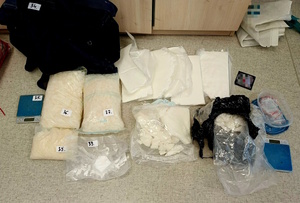 narkotyki leżą na podłodze. Policjant sprawdza i ogląda zawartość.