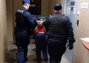 Policjanci prowadzą zatrzymanego za spowodowanie ciężkiego uszczerbku na zdrowiu.