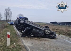 Leżące na dachu auto, z tyłu widać policyjny radiowóz.