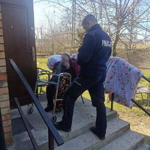 dwóch policjantów pozuje do zdjęcia stoją na tle radiowozu.