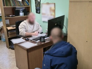 Policjant prowadza czynności procesowe z osobą zatrzymaną.