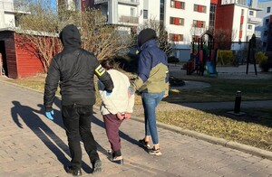 Dwaj policjanci prowadzą kobietę.