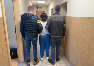 Dwaj policjanci prowadzą kobietę.