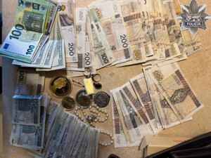 Banknoty, biżuteria i monety rozłożone na stole.