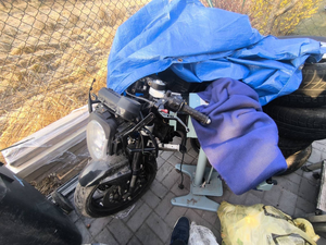 Policjanci prowadzą zatrzymanych. Kable porozkładane na ziemi w pudełkach i kartonach.