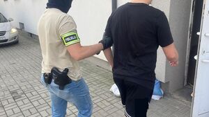 policjant prowadzi zatrzymanego.