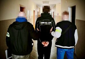 dwóch policjantów prowadzi zatrzymanego.