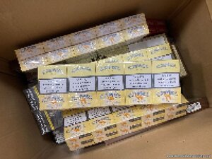 policjanci prowadzą zatrzymanego. Papierosy bez akcyzy leżą porozkładane w kartonach.