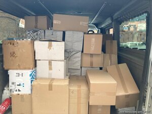 policjanci prowadzą zatrzymanego. Papierosy bez akcyzy leżą porozkładane w kartonach.