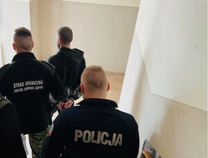 policjanci i funkcjonariusz Staraży Granicznej prowadzą zatrzymanego.