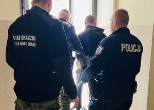 policjanci i funkcjonariusz Staraży Granicznej prowadzą zatrzymanego.