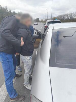 Funkcjonariusz z zatrzymanym przy radiowozie.