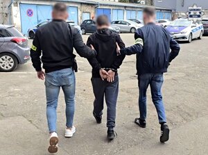 policjanci przesłuchują mężczyznę który siedzi na krześle.