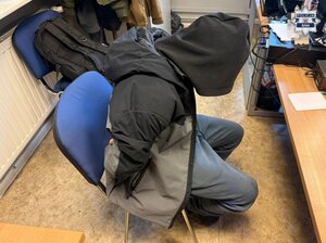 policjanci przesłuchują mężczyznę który siedzi na krześle.