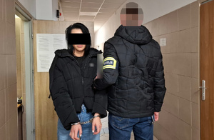 Policjant prowadzi zatrzymaną.