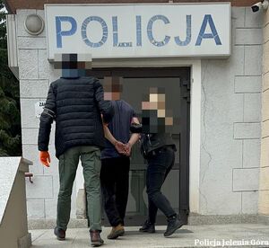 policjanci prowadzą zatrzymanego,  pistolet lezy na stole.