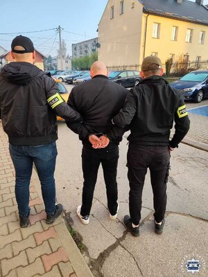 Zatrzymany pseudokibic prowadzony przez policjantów.