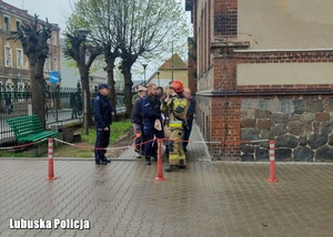 Policjanci i strażacy stoją obok budynku.