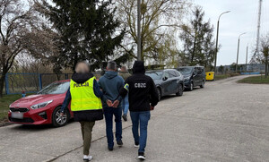 policjanci prowadzą zatrzymanego.