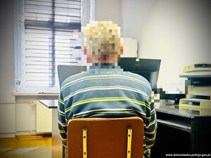 mężczyzna siedzi na krześle, ma ręce skute kajdankami.