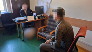 Mężczyzna zatrzymany przez policjantów siedzi na krześle w trakcie przesłuchania.