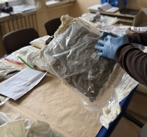 policjanci prowadza zatrzymanego, Na stole w workach plastikowych porozkładane marihuana, kryształ.