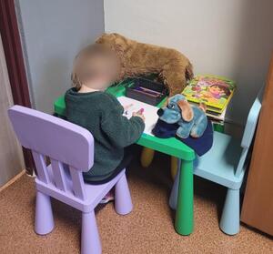 Dziecko siedzi przy stoliku i rysuje na kartce.