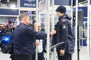 Zdjęcie przedstawia eksperta z obszaru umundurowania i wyposażenia specjalnego przedstawiającego zainteresowanym nowe i/lub unowocześnione elementy asortymentu