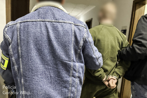 Policjanci prowadza zatrzymanego w kajdankach.
