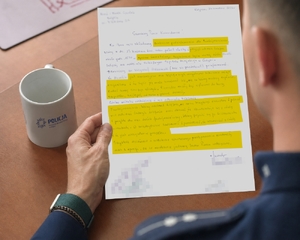 policjant trzyma w ręku list z podziękowaniami.