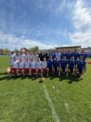 Reprezentacja kobiet i mężczyzn pozuje na boisku do zdjęcia.