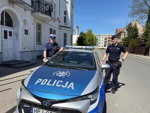Policjanci stoją przy radiowozie.