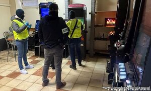 Policjant i funkcjonariusze służby celno skarbowej przy automacie do gier.