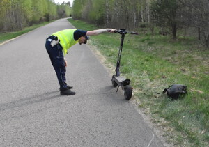 Policjant ogląda hulajnogę elektryczną.