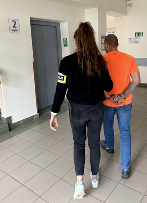 Policjantka prowadzi zatrzymanego.