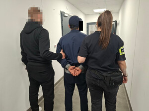 Zatrzymany 37-latek trzymany przez policjanta i policjantkę.