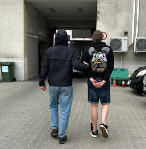 Funkcjonariusz prowadzi zatrzymanego.