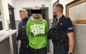 policjanci prowadzą zatrzymanego.