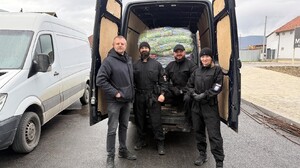 Policjanci przy samochodzie ładują karmę dla psów.