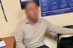 Zatrzymany mężczyzna siedzi na krześle w trakcie przesłuchania.