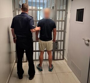 policjant stoi z zatrzymanym.