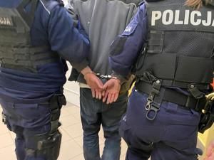Dwaj policjanci prowadzą zatrzymanego.