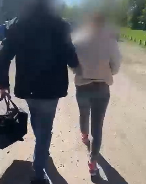Policjant prowadzi zatrzymana osobę.