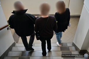 Funkcjonariusze prowadzą zatrzymaną kobietę.