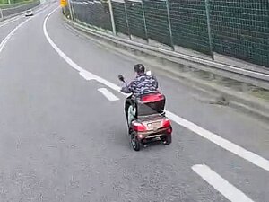 Mężczyzna na elektrycznym wózku inwalidzkim jedzie drogą.